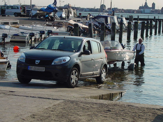 Slipping des Bootes, welches vom Bootshänger gelassen wird, das Zugfahrzeug steht mit den Hinterrädern halb im Wasser